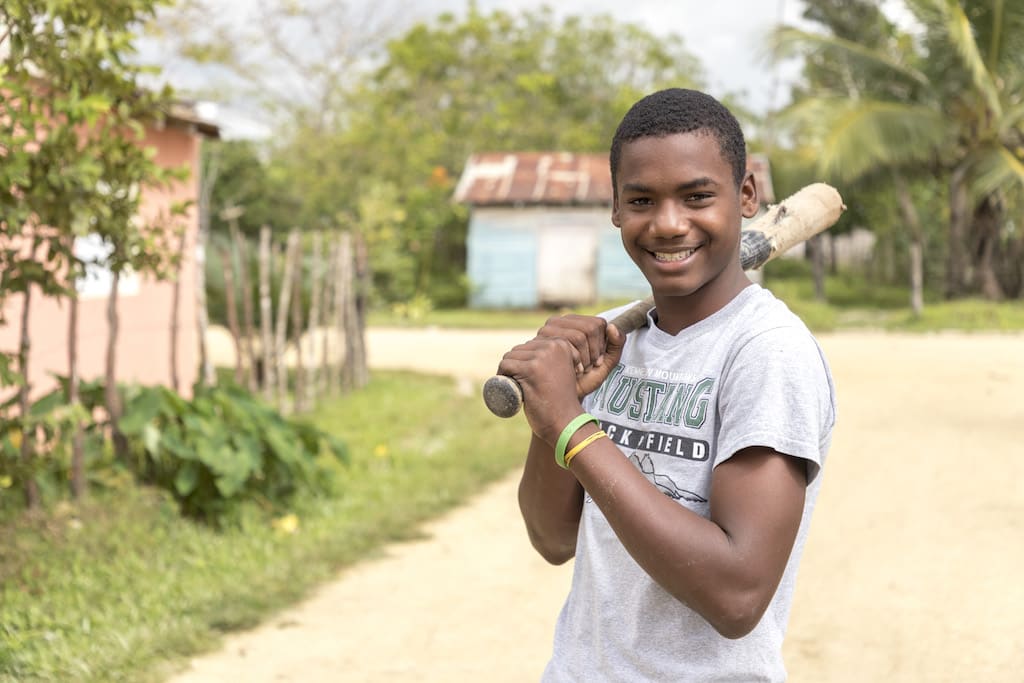 Julio smiling and posing with a baseball bat over his shoulder.